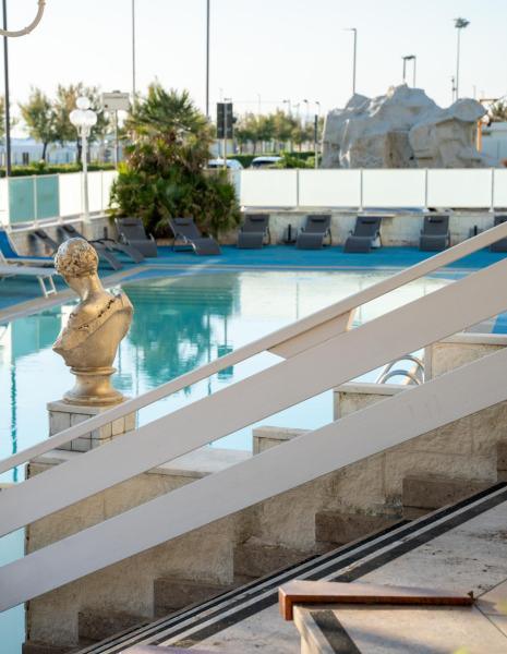 Piscine avec statues et transats, cadre tranquille.