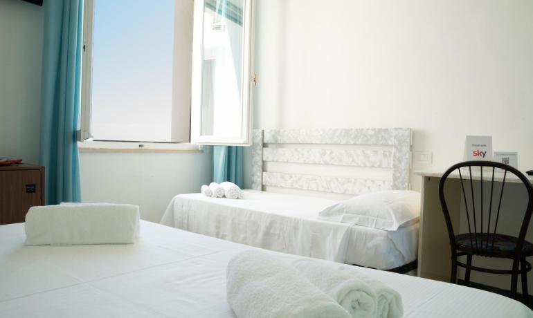 Bright room with beds and white towels, open window.