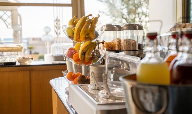 Buffet with fruit, cereals, and juices in a bright setting.